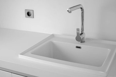 Lavabo ve krom musluklu modern banyo. Beyaz renk arkaplanı