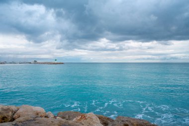 Bulutlu gökyüzünün altındaki güzel gök mavisi deniz fenerinde.