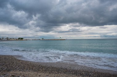 Bulutlu gökyüzünün altındaki güzel gök mavisi deniz fenerinde. Panoramik deniz manzarası