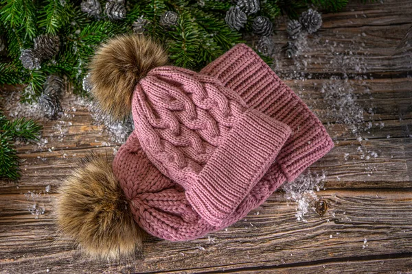 Anne ve kız için ponponlu, sıcak, pembe şapkalar. Ahşap arka planda Noel süslemesi, düz yatış. 