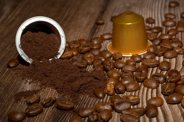 İçinde öğütülmüş kahve olan Espresso kahve kapsülünü açın. Kahveler ve kavrulmuş kahve çekirdekleri ahşap arka planda. Yüksek kalite fotoğraf