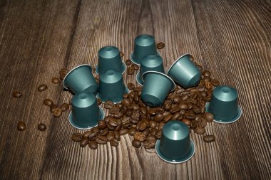 Espresso kahve kapsülleri ya da ahşap zemin üzerinde kavrulmuş kahve çekirdekleri. Yakın plan.