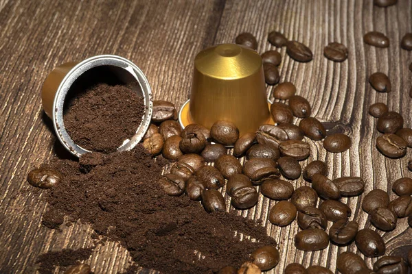 Open Espresso coffee capsule with grounded coffee inside. Coffee pods and roasted coffee beans on wooden background. High quality photo