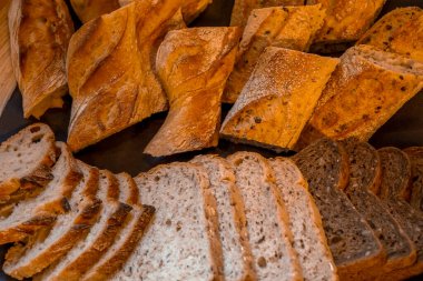 Otelin kahvaltısında taze ekmek ve ahşap tabak. Farklı ekmek dilimleri. Kahverengi ve beyaz kepekli tahıl. Gıda arkaplanı.