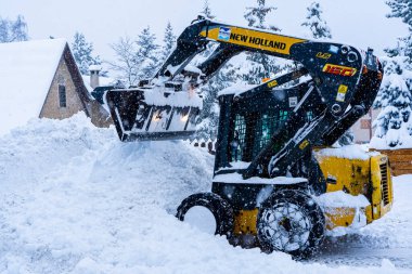 Auron, Fransa 01.01.2021 Yoğun bir kar yağışı altında bir kayak merkezinde kar temizleyen bir traktör. Dağ köyü