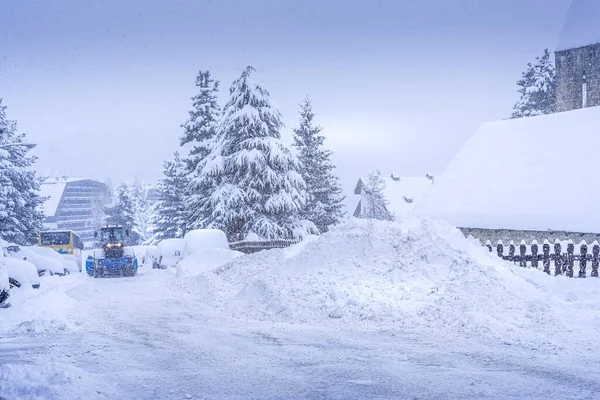 Auron, Fransa 01.01.2021 Yoğun bir kar yağışı altında bir kayak merkezinde kar temizleyen bir traktör. Dağ köyü — Stok fotoğraf