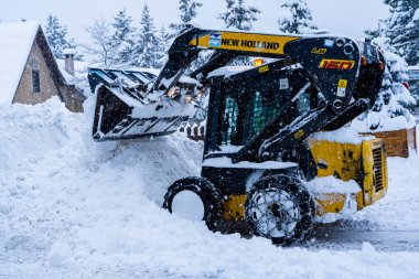 Auron, Fransa 01.01.2021 Yoğun bir kar yağışı altında bir kayak merkezinde kar temizleyen bir traktör. Dağ köyü