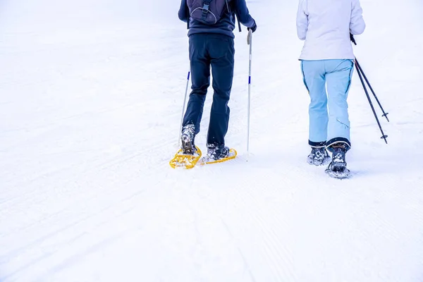 Winterwandeling met sneeuwschoenen en wandelschoenen. Sneeuwschoenwandelaars rennen in poedersneeuw. Outdoor winteractiviteit en gezonde levensstijl. — Stockfoto