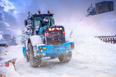 Auron, Fransa 01.01.2021 Traktör kayak merkezinin yanındaki büyük kar yığınlarından karı kaldırıyor..