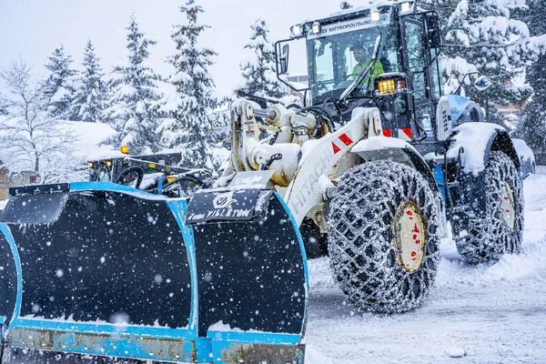 Auron, Fransa 01.01.2021 Traktör Fransız Alpleri 'ndeki kayak merkezinin yanındaki yoldaki büyük kar yığınlarından karı kaldırıyor. — Stok fotoğraf