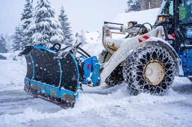 Auron, Fransa 01.01.2021 Traktör Fransız Alpleri 'ndeki kayak merkezinin yanındaki yoldaki büyük kar yığınlarından kar temizliyor. Yüksek kalite fotoğraf