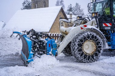 Auron, Fransa 01.01.2021 Traktör Fransız Alpleri 'ndeki kayak merkezinin yanındaki yoldaki büyük kar yığınlarından karı kaldırıyor.