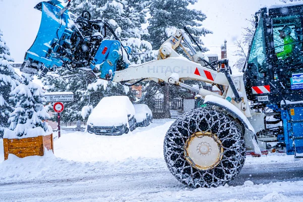 Auron, Fransa 01.01.2021 Traktör Fransız Alpleri 'ndeki kayak merkezinin yanındaki yoldaki büyük kar yığınlarından karı kaldırıyor. — Stok fotoğraf