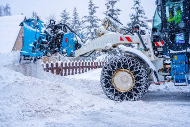 Auron, Fransa 01.01.2021 Traktör Fransız Alpleri 'ndeki kayak merkezinin yanındaki yoldaki büyük kar yığınlarından kar temizliyor. Yüksek kalite fotoğraf