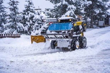 Auron, Fransa 01.01.2021 Traktör Fransız Alpleri 'ndeki kayak merkezinin yanındaki yoldaki büyük kar yığınlarından kar temizliyor. Yüksek kalite fotoğraf