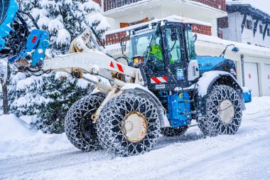 Auron, Fransa 01.01.2021 Traktör Fransız Alpleri 'ndeki kayak merkezinin yanındaki yoldaki büyük kar yığınlarından kar temizliyor. Yüksek kalite fotoğraf