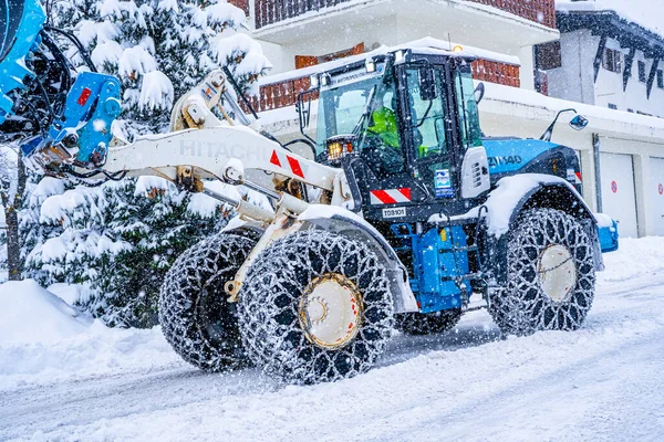 Auron, Fransa 01.01.2021 Traktör Fransız Alpleri 'ndeki kayak merkezinin yanındaki yoldaki büyük kar yığınlarından kar temizliyor. Yüksek kalite fotoğraf