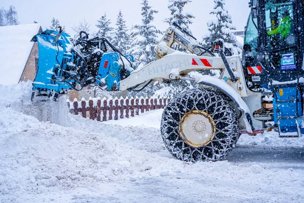 Auron, Fransa 01.01.2021 Kayak merkezindeki karla kaplı yolları temizleyen bir kar yağıcı. Seçici odaklanma. Kar ve yağmur kavramı. Kar yükleyici köydeki karları temizler..