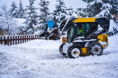 Auron, Fransa - 01.01.2021: Tekerlek yükleme makinesi bir kayak merkezindeki karı temizliyor. Kardan yolu temizliyorum.