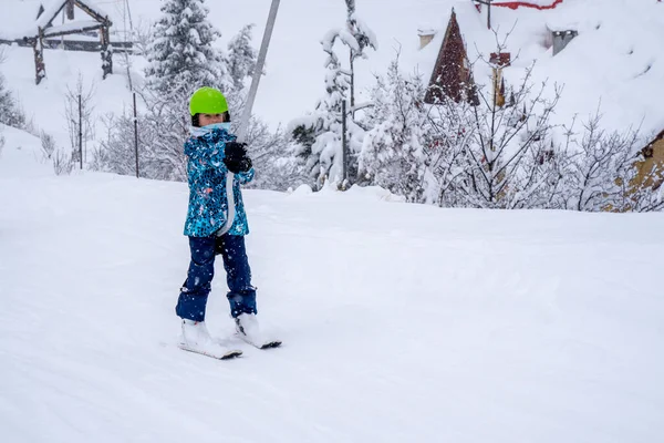 Θολή εστίαση φόντου. Ένα κορίτσι που σηκώνεται στο σχοινί του τελεφερίκ σκι σε μπλε φόρμα σπορ στο βουνό χιονοδρομικό κέντρο κάνει ένα μάθημα σκι κατά τη διάρκεια μιας χιονοπτώσεις. Χιονοδρομικό θέρετρο στα γαλλικά βουνά. — Φωτογραφία Αρχείου