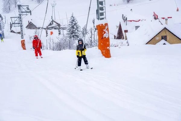 AURON, FRANKRIJK - 01.01.2021: Professionele skileraar en kinderlift op het skiliften touw naar de berg tijdens de sneeuwval. Familie en kinderen actief vakantie concept. — Stockfoto