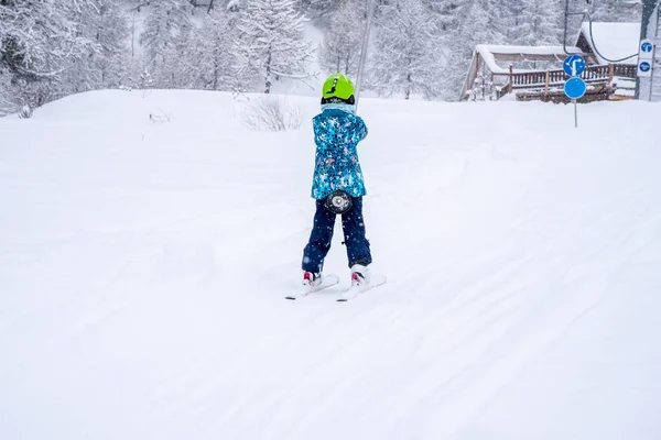 Fondo de enfoque borroso. Una chica que se levanta en la cuerda del telesilla en traje deportivo azul en la montaña de la estación de esquí hace una lección de esquí durante una nevada. Estación de esquí en montañas francesas. —  Fotos de Stock