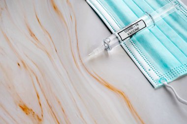 Medical mask and syringe with liquid medicine, preparing for vaccination. Healthcare concept. Protection from viruses, flu, coronavirus. 
