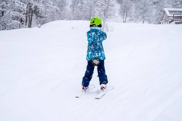 Bulanık odak arkaplanı. Kayak merkezindeki dağda mavi spor kıyafetiyle kayak kaldıran bir kız kar yağışı sırasında kayak dersi verir. Fransız dağlarında kayak merkezi.. — Stok fotoğraf