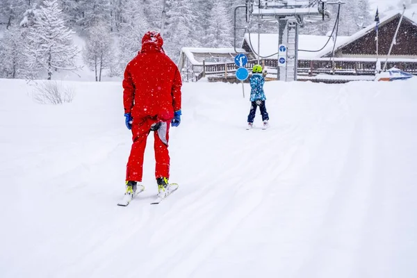 AURON, FRANCIA - 01.01.2021: Maestro di sci professionista e baby lifting sulla funivia per la montagna durante la nevicata. Famiglia e bambini concetto di vacanza attiva. — Foto Stock