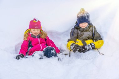 Çocuklar Karlı Şelalenin ve Karda Oynamanın tadını çıkarıyor. Kış tatili Açık hava oyunları. Sıcak kıyafetler, soğuk havada rahat şapka.