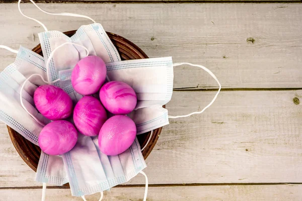 Paskalya geleneksel pembe yumurtaları ve koruyucu maskeleri sepette COVID-19 ya da koronavirüs salgını için konsept olarak kullanılıyor. Aşı ve bağışıklık konsepti