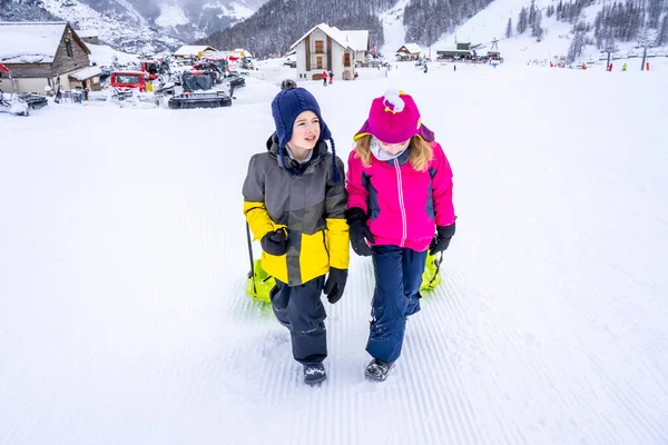 AURON, FRANCE - 30.12.2020: Ευτυχισμένο αγόρι και κορίτσι με έλκηθρο χιονιού σε χειμερινό χιονοδρομικό κέντρο. — Φωτογραφία Αρχείου