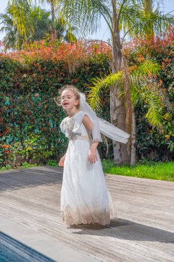 Havuzun yanındaki palmiye bahçesinde beyaz tül elbiseli duygusal sarışın kız dans ediyor. Romantik bir kavram. Yüksek kalite fotoğraf