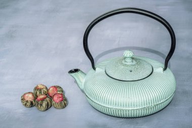 Demir çaydanlık ve gri arka planda aromatik yeşil çay çiçekli top kompozisyonu. Asya geleneği çay töreni.