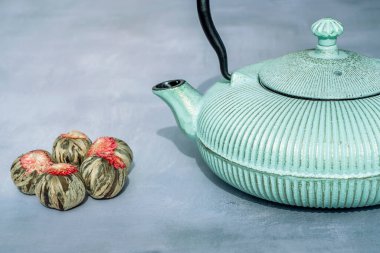 Demir çaydanlık ve gri arka planda aromatik yeşil çay çiçekli top kompozisyonu. Asya geleneği çay töreni.