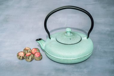 Demir çaydanlık ve gri arka planda aromatik yeşil çay çiçekli top kompozisyonu. Asya geleneği çay töreni.