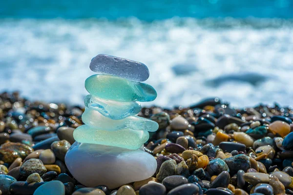 Sahildeki denge piramidine yerleştirilmiş deniz camı taşları. Bulanık deniz manzaralı güzel gök mavisi deniz. Meditasyon ve Uyum kavramı
