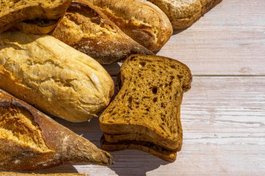 Ahşap yüzeyde farklı türde taze ekmek. Kapatın. Fırın kavramı. 