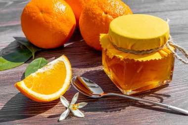 Geleneksel portakal reçeli ve ahşap arka planda taze portakal meyveleri. Durgun hayat. Minimum gıda konsepti. Acımasız gölge. Düz yatıyordu. 