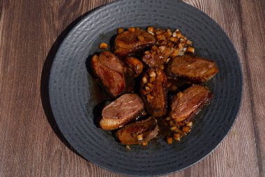 Duck breast fillet served on a black plate, fried with garlic, special asiatic soy sauce recipe. High quality photo