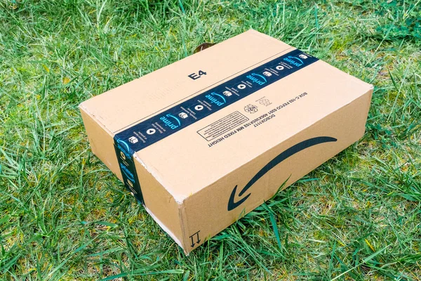 Güzel, France- 14.04.2021 Amazon Prime logotype 'un üstünden ön taraftaki karton kutunun güvenlik bandına basılmış görüntüler. Yeşil çimen arkaplanı