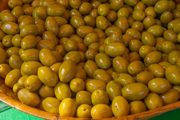 Green pickled Olives at the weekly market in french province. Background of olives in a bowl, close up.