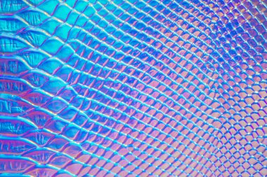 Holografik parlak gökkuşağı çok renkli soyut bir arkaplan. Metalik makro yakın çekim. Gökkuşağı renginin taklidi. Pembe ve mavi tonlarda sürüngen derisi olan bir arka plan.