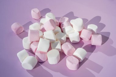 Pembe arka planda renkli mini marşmelovlar. Düz yerde, üst tarafta. Çocuklar tatil yiyecekleri konsepti.