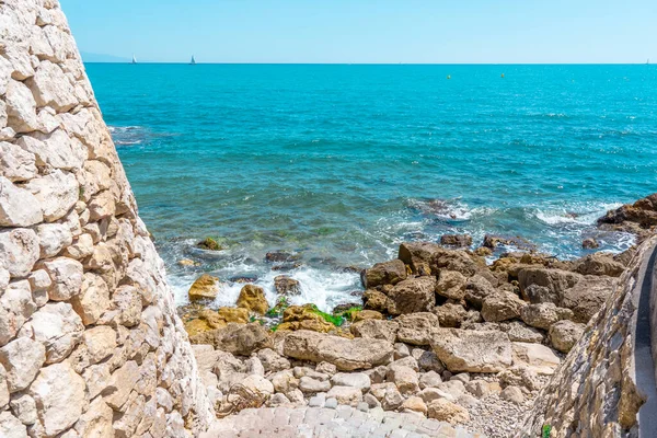 Fortress and a staircase made from stones, going into the sea. Many big and small rocks and sea waves hitting the rocks. Blue sea waves background and sky beautiful landscape. — Stock Photo, Image