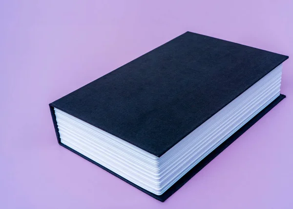 Big black book on violet isolated background with copy space for your text. — Stock Photo, Image