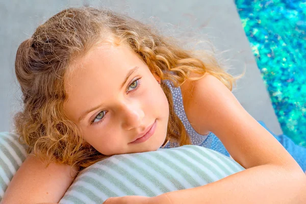 Retrato de una hermosa joven relajándose en una silla cerca de la piscina. Joven modelo tumbado en la tumbona. Imagen De Stock