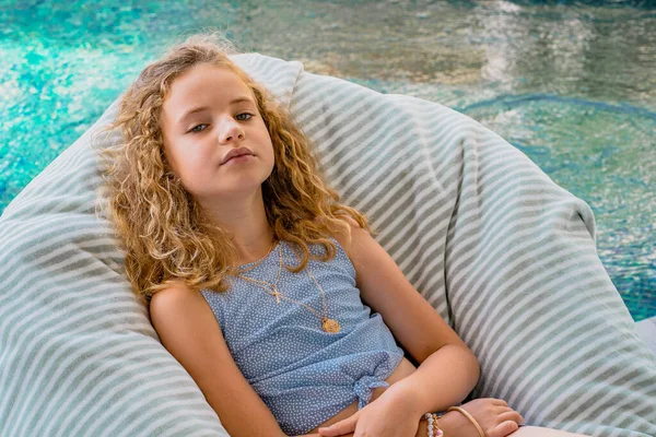 Bella ragazza che si rilassa su una sedia vicino alla piscina. Giovane modella sdraiata sul lettino. — Foto Stock