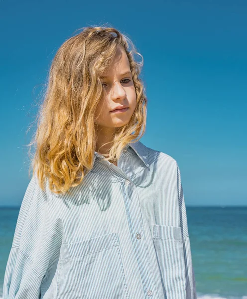 Молодая красивая девушка в синем платье, остановившаяся на песчаном пляже возле волн. — стоковое фото