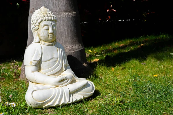 Buddha fehér szobor közel a fához a kertben. A buddhizmus alapítója. Közelről. — Stock Fotó